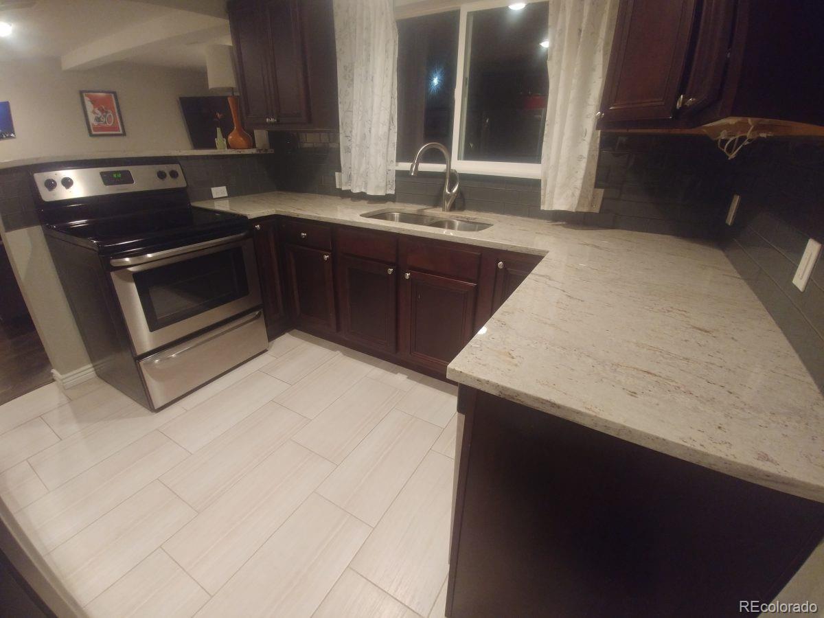 2918 Ames Street Wheat Ridge, CO 80214 - Photo 8 of 19 a kitchen with a sink and a stove with wooden cabinets