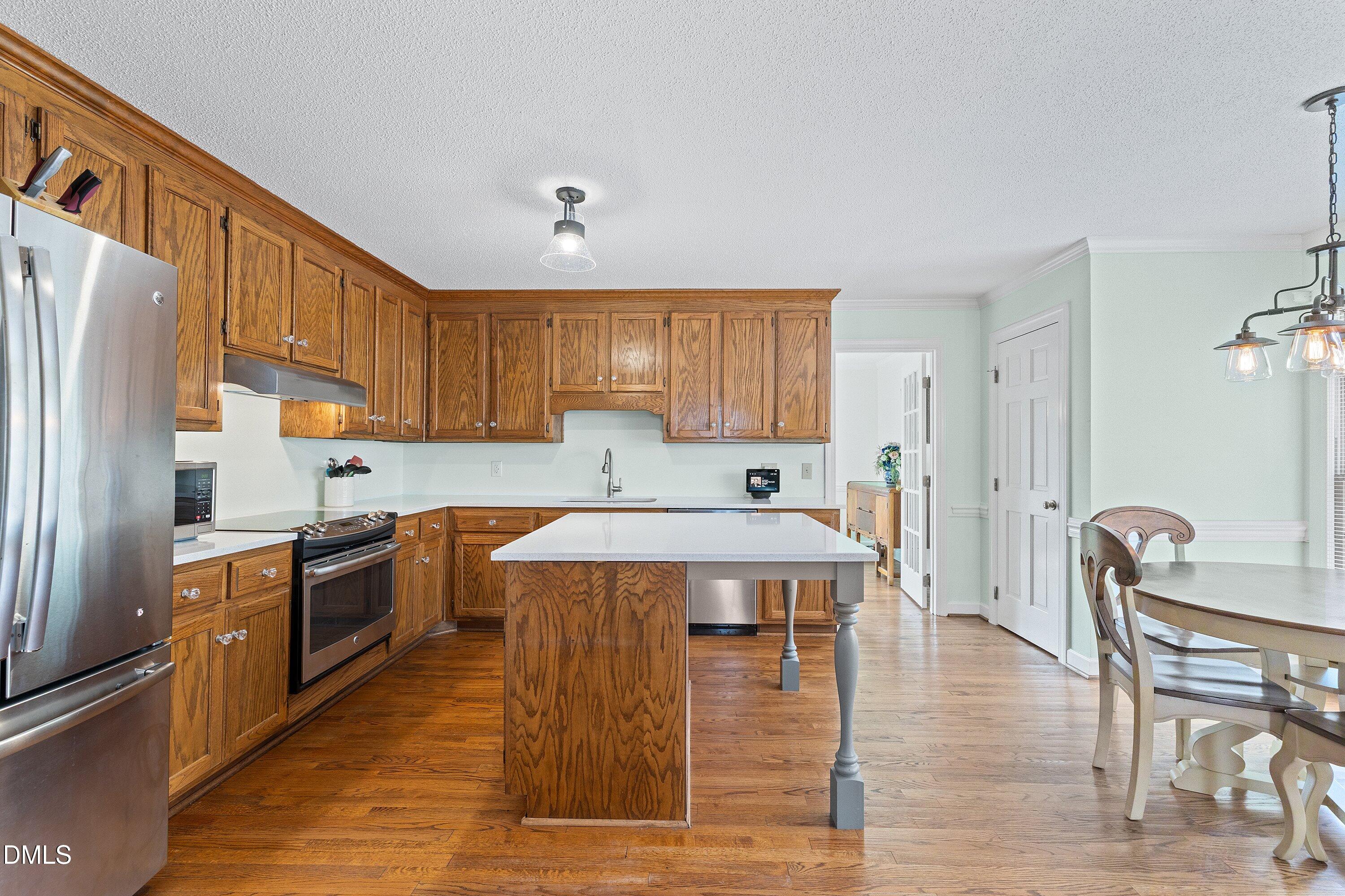 2500 Cravenridge Road Garner, NC 27529 - Photo 13 of 52 a large kitchen with stainless steel appliances granite countertop a stove top oven a refrigerator a dining table and chairs with wooden floor