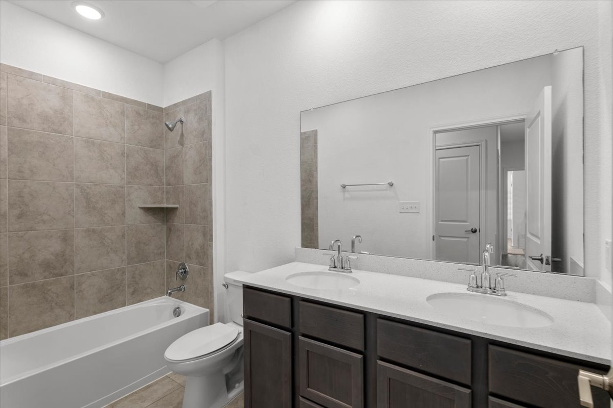 500 Stinchcomb Road Hutto, TX 78634 - Photo 27 of 37 A well-appointed bathroom features a shower-tub combination, dual vanities, and reflective surfaces.