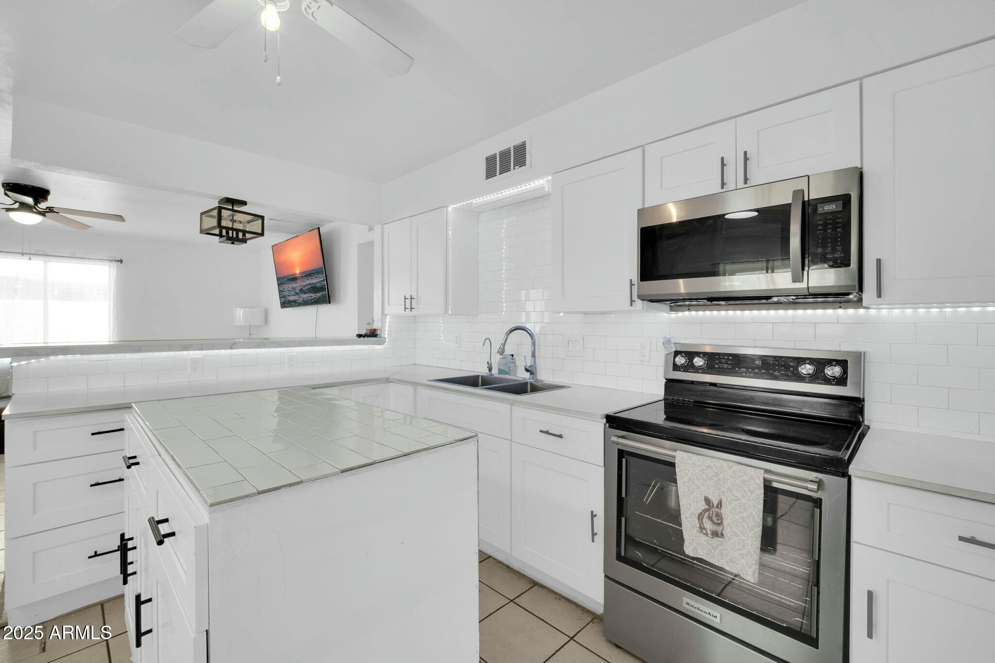 2929 West Granada Road Phoenix, AZ 85009 - Photo 7 of 28 a kitchen with stainless steel appliances a stove microwave and sink