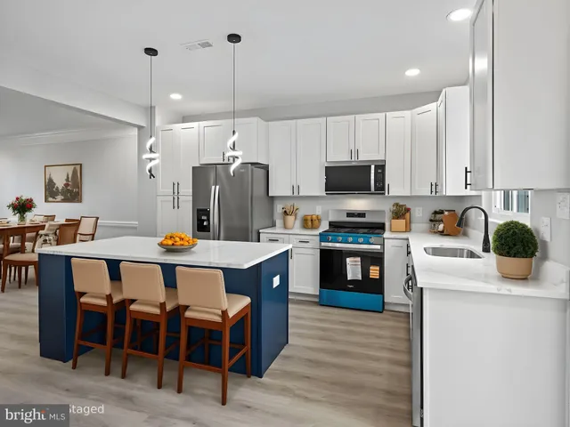 a kitchen with a chandelier stainless steel appliances and white cabinets