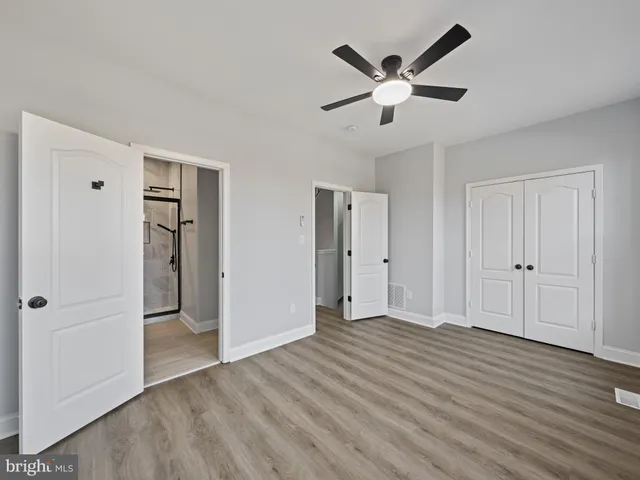 a view of empty room with wooden floor and ceiling fan