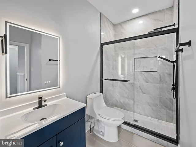 a bathroom with a shower sink vanity mirror and toilet