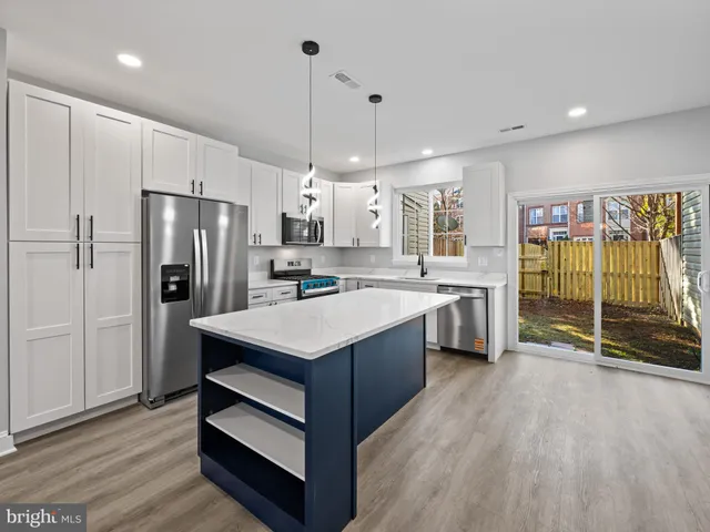 a kitchen with kitchen island a counter top space a sink stainless steel appliances and cabinets