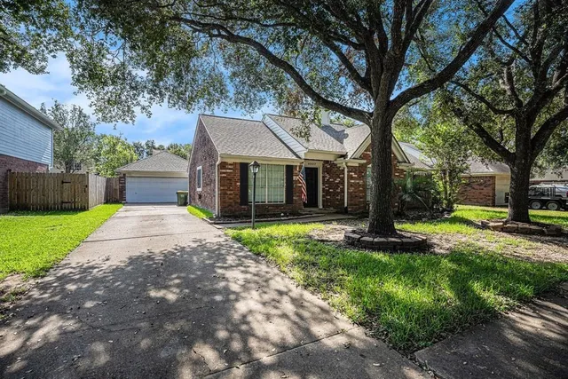 a view of a house with a yard and large tree