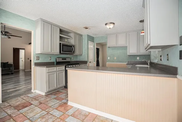 a kitchen with granite countertop a stove a sink and a microwave