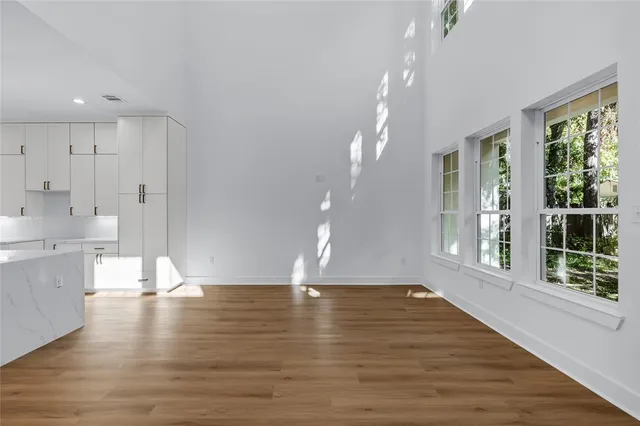 a view of an empty room with kitchen and window
