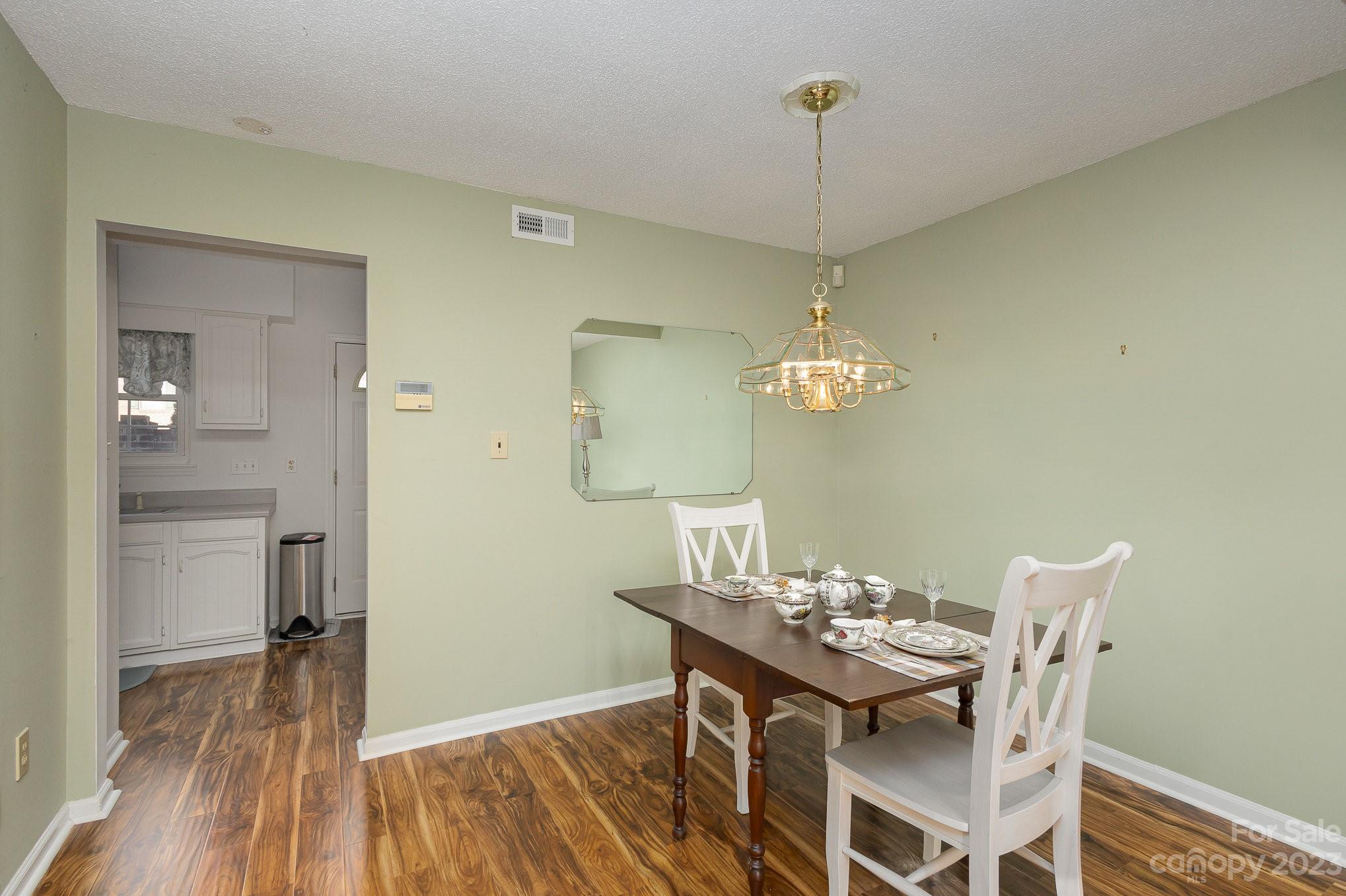 10927 Park Road Charlotte, NC 28226 - Photo 7 of 28 a dining room with wooden floor a chandelier a wooden table and chairs