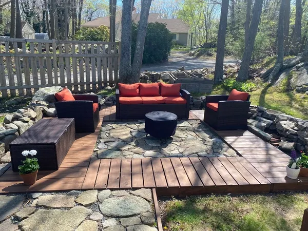 a view of a patio with couches chairs and a fire pit with large trees