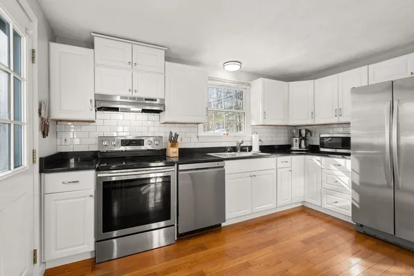 a kitchen with stainless steel appliances white cabinets a sink a stove a microwave and cabinetry