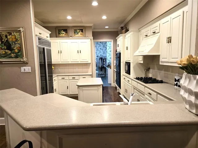a kitchen with stainless steel appliances kitchen island granite countertop a refrigerator oven a sink and white cabinets