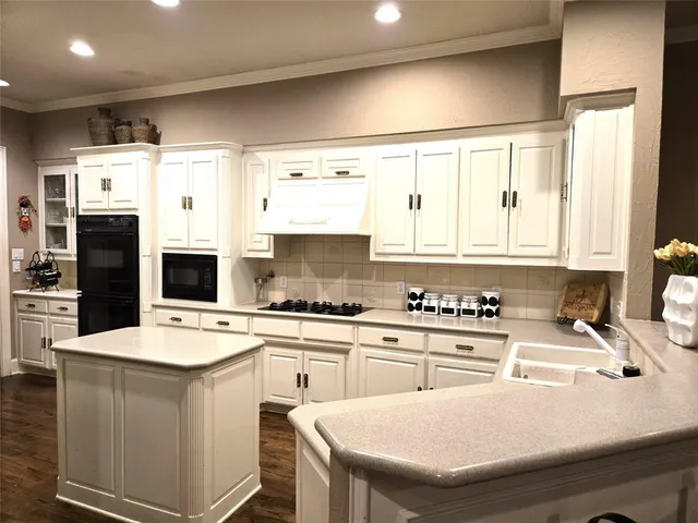 a kitchen with granite countertop a sink stainless steel appliances and white cabinets