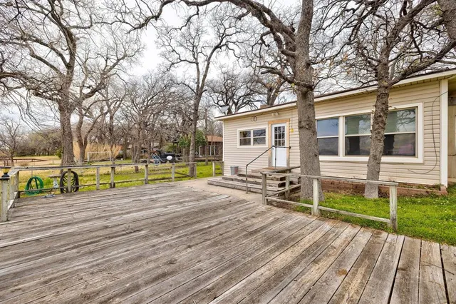 a view of a house with wooden deck and trees