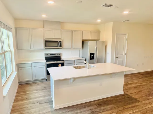 a kitchen with kitchen island a sink stainless steel appliances and cabinets