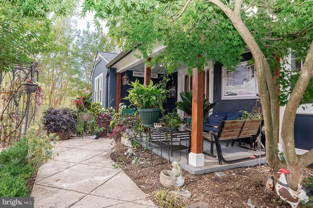 a view of a patio with table and chairs potted plants and large tree