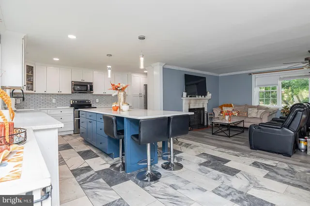 a living room with stainless steel appliances kitchen island granite countertop furniture a rug kitchen view and a window