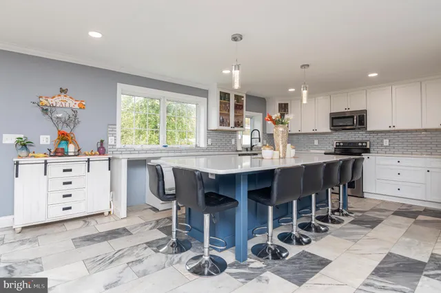 a kitchen with stainless steel appliances kitchen island granite countertop a table chairs and a refrigerator