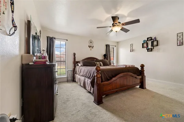 a bedroom with a bed lamp and a ceiling fan