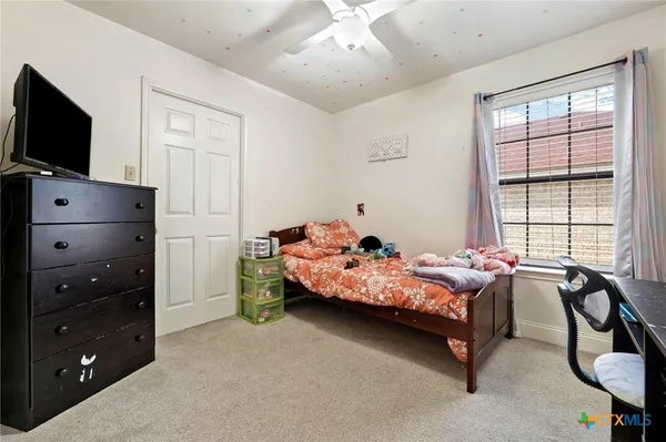 a bedroom with a bed and a flat tv screen on dresser