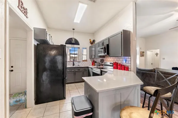 a kitchen with stainless steel appliances kitchen island granite countertop a refrigerator a stove a microwave and chairs