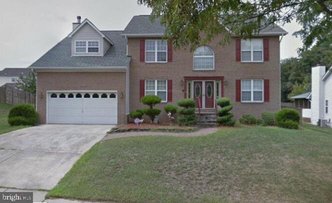 a front view of a house with yard and parking