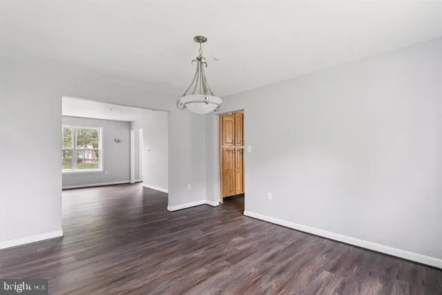a view of empty room with wooden floor and window