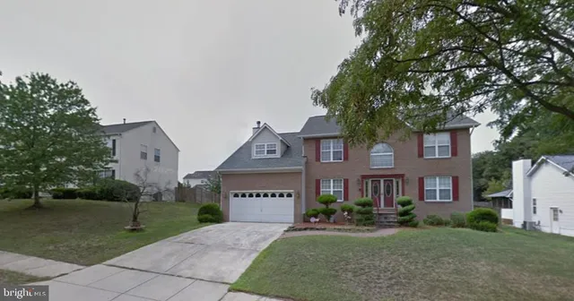 a front view of a house with a garden and trees