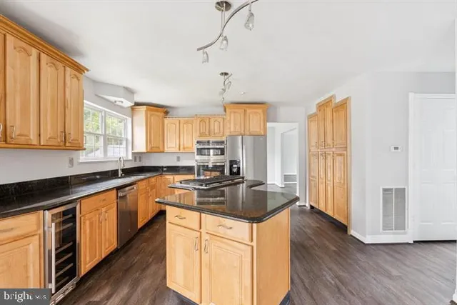 a kitchen with stainless steel appliances granite countertop a stove a sink dishwasher and a refrigerator with wooden floor