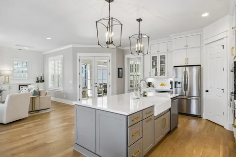 a large kitchen with kitchen island granite countertop a refrigerator a stove a sink dishwasher and white cabinets with wooden floor