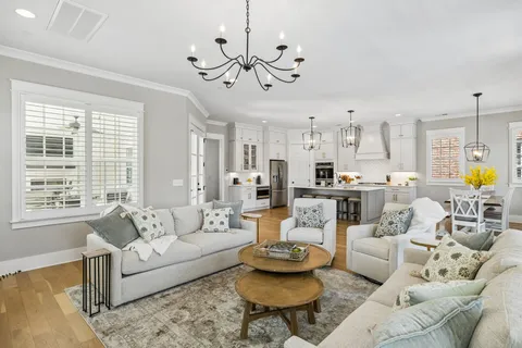 a living room with furniture kitchen view and a chandelier