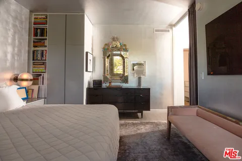 a bedroom with a bed mirror and window