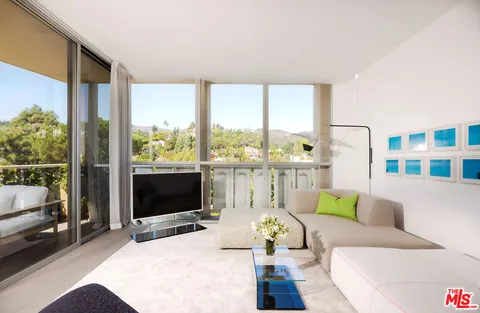 a living room with furniture tv and a floor to ceiling window