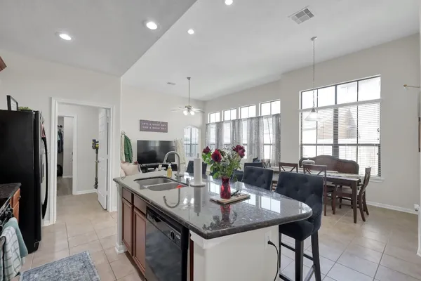 a kitchen with stainless steel appliances granite countertop a stove a refrigerator a sink a dining table and chairs