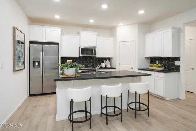 a kitchen with stainless steel appliances granite countertop a stove top oven a sink a dining table and chairs