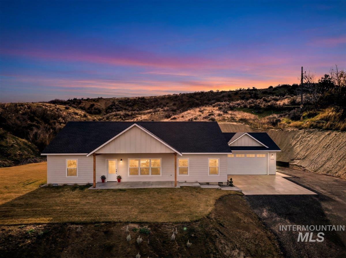 Ranch-style home featuring driveway, a porch, a lawn, board and batten siding, and roof with shingles