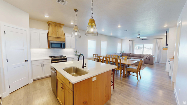 1127 4240 North Enoch, UT 84721 - Photo 55 of 56 Kitchen featuring light wood-style flooring, a kitchen island with sink, stainless steel appliances, open floor plan, and backsplash