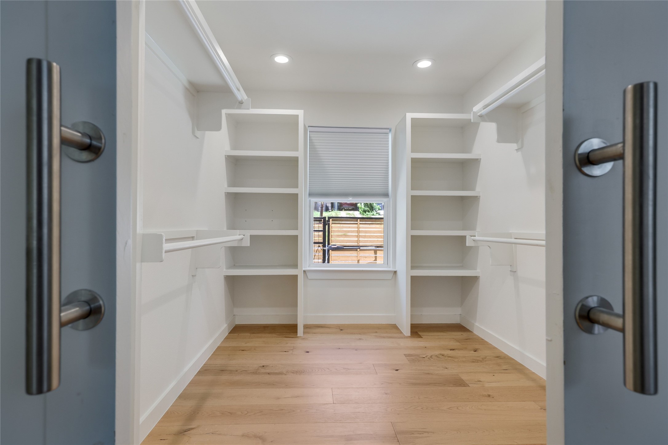 5203 Ledesma Road Austin, TX 78721 - Photo 21 of 40 Ample built-in shelving and hanging space define this primary walk-in wardrobe, illuminated by natural light and recessed fixtures.