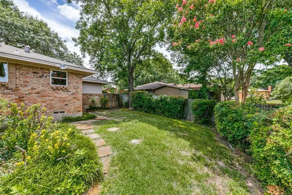 a backyard of a house with plants and large tree