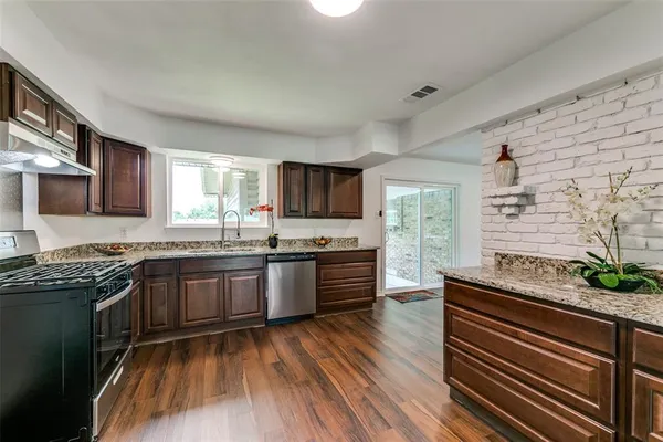 a kitchen with stainless steel appliances granite countertop wooden cabinets stove top oven and sink