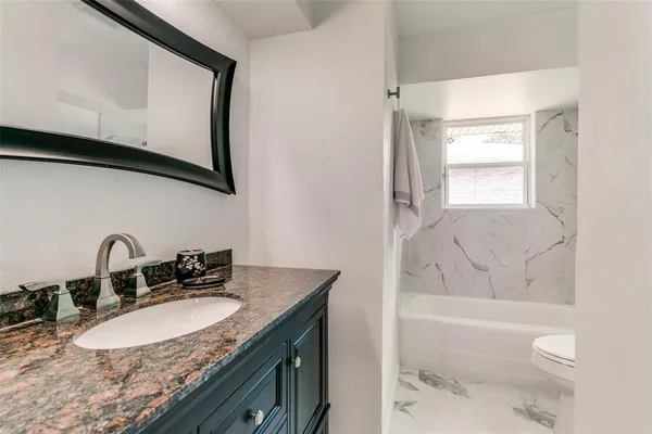 a bathroom with a granite countertop sink a toilet and bathtub