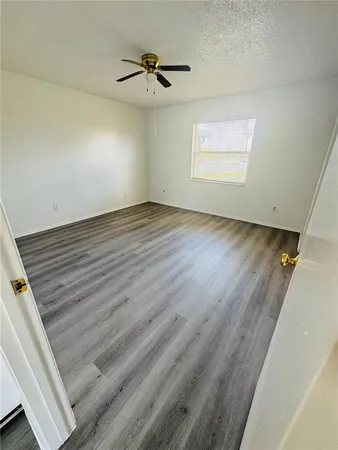 an empty room with wooden floor a ceiling fan and window