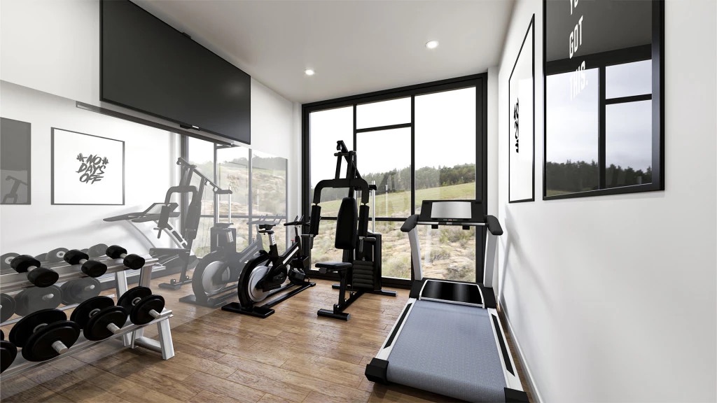 Floor-to-ceiling windows frame natural hillside views from this dedicated home exercise space with wood-style flooring.