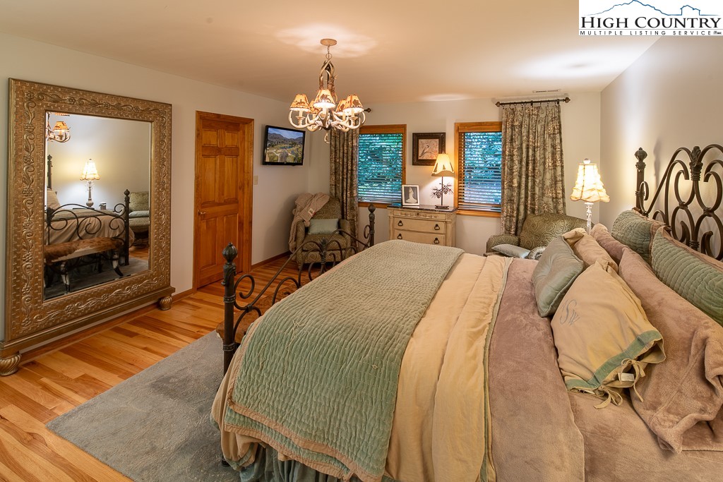 127 Apple Tree Boone, NC 28607 - Photo 27 of 50 a spacious bedroom with a bed a chandelier and a flat tv screen