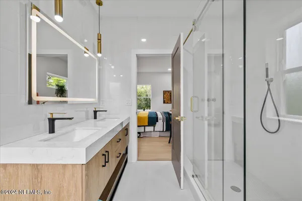 a bathroom with a double vanity sink a mirror a bathtub and a shower