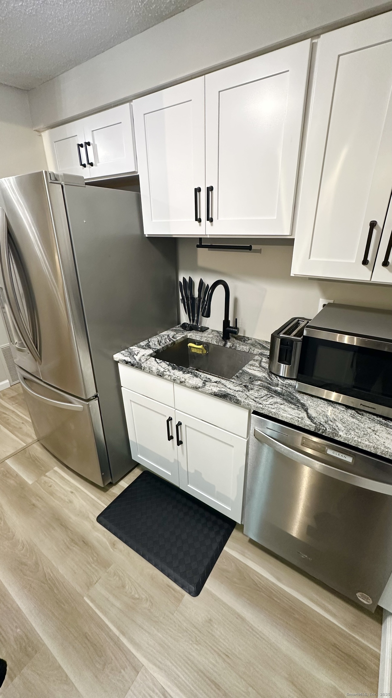 105 Tremont Avenue, Unit B Bridgeport, CT 06606 - Photo 12 of 24 a kitchen with a sink a refrigerator and cabinets
