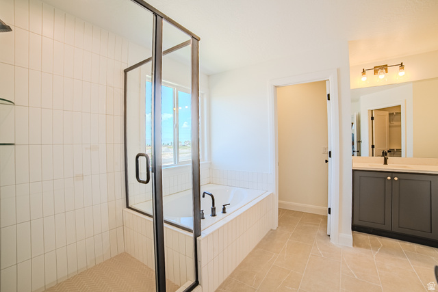 45 North Scarlet Maple Road, Unit 4317 Vineyard, UT 84059 - Photo 16 of 35 Contemporary bathroom featuring a walk-in shower with vertical subway tile, a built-in soaking tub, a dark gray vanity with a light-colored countertop, and a large window providing ample natural light