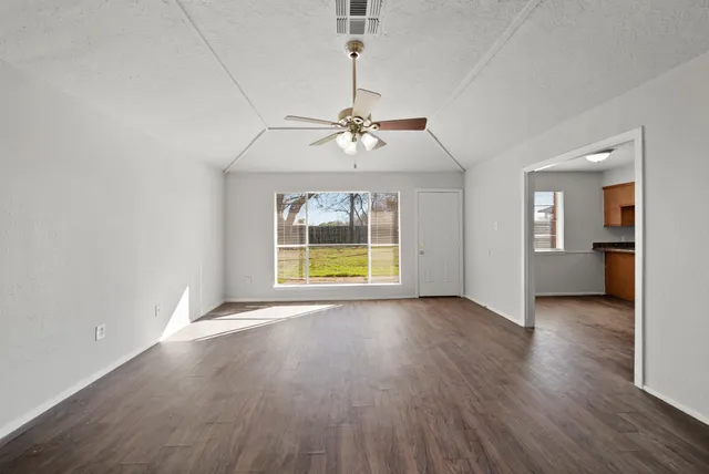 a view of an empty room with a window and wooden floor