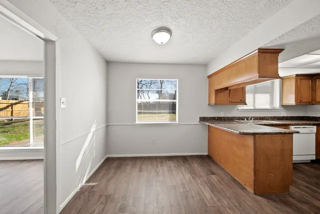 a view of a kitchen with stainless steel appliances granite countertop a stove and a wooden floors