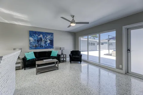 a living room with furniture a ceiling fan and a floor to ceiling window