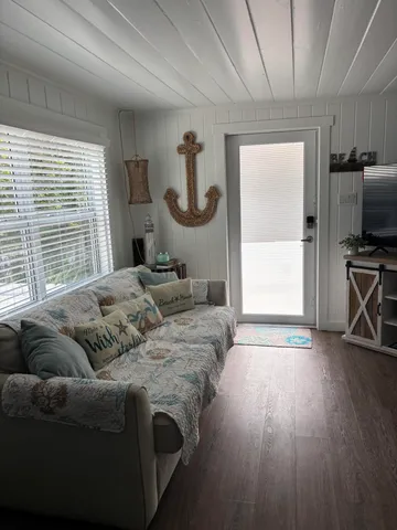 a living room with furniture a flat screen tv and a large window